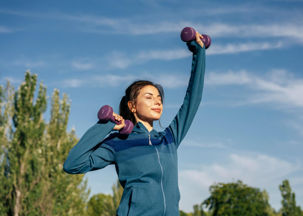 medium shot woman practicing with dumbbells