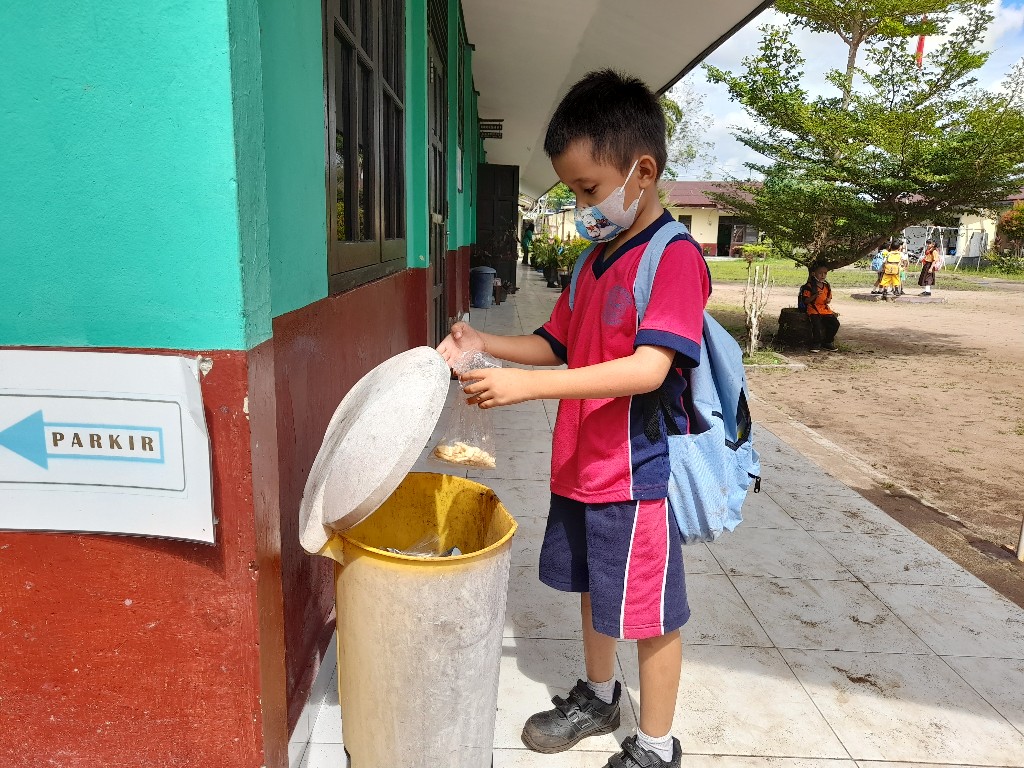 Siswa membuang sampah pada tempatnya