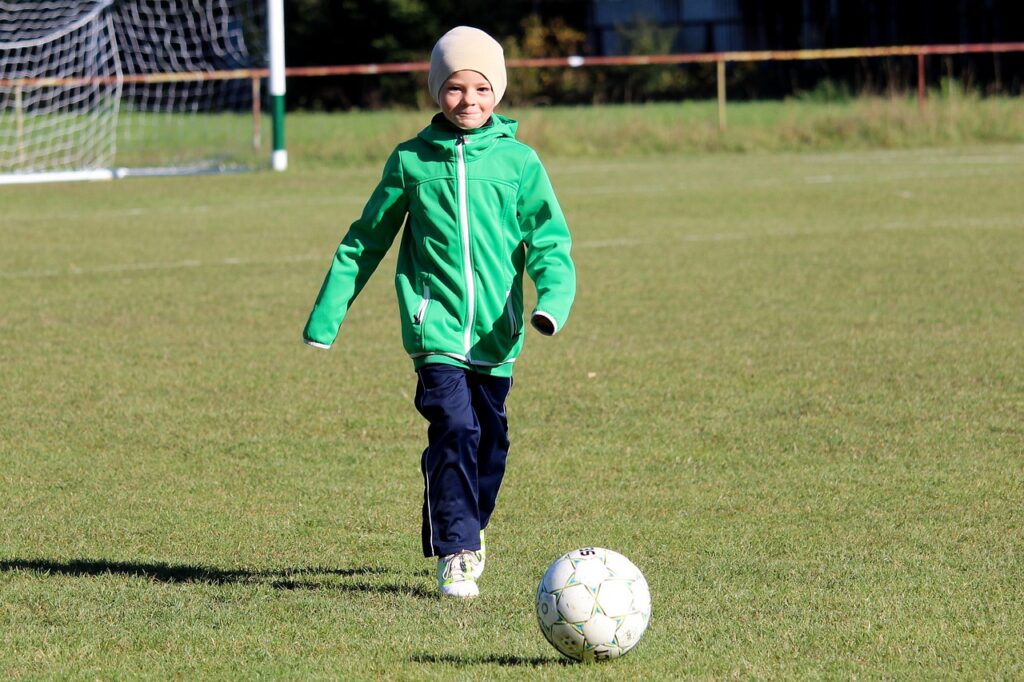 Anak tersenyum bermain sepak bola 