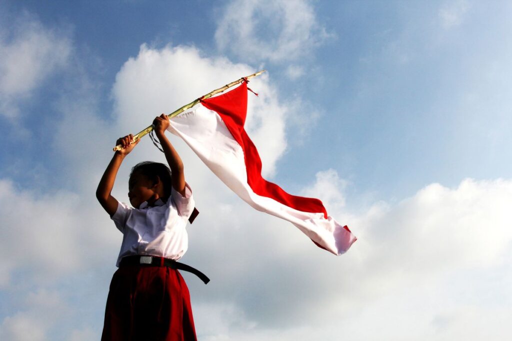 Siswi sedang mengibarkan bendera Indonesia