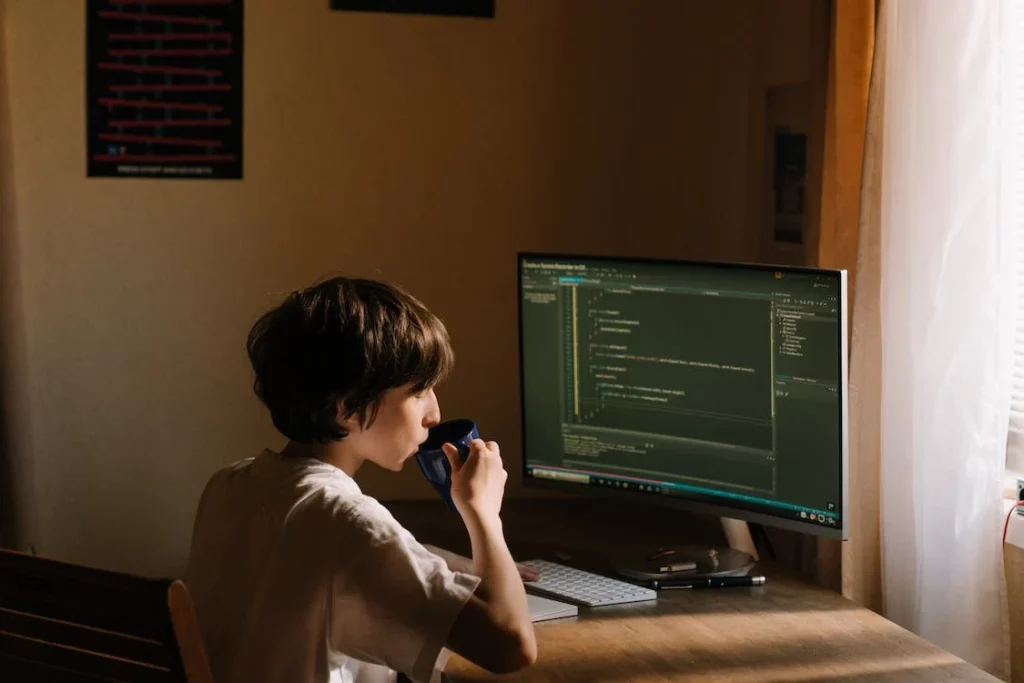 Anak laki-laki sedang duduk di depan komputer